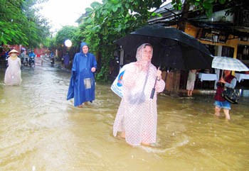 Foreign visitors wading through flooded road in Hoi An ancient town in Quang Nam Province (Photo: SGGP)